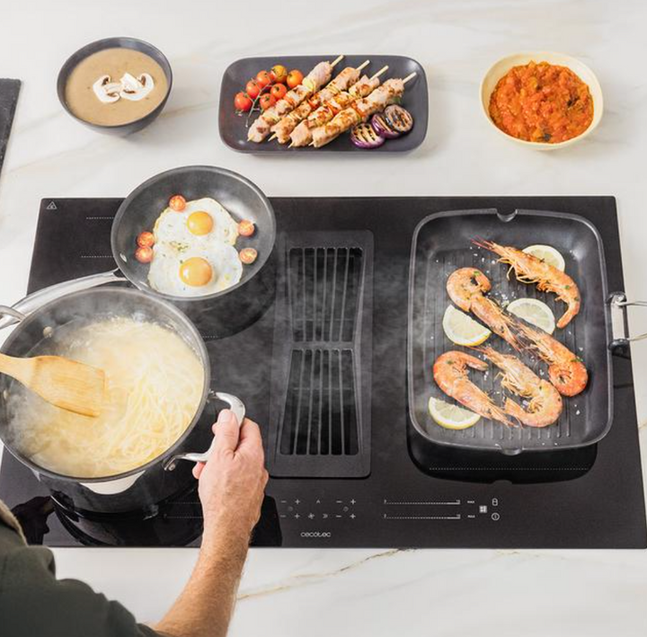 Plaque à induction avec hotte aspirante intégrée / A01_EU01_100088 Plaque à induction avec 2 foyers TotalFlex et hotte aspirante intégrée, puissance maximale de 7400 W, 15 niveaux avec fonction Booster, minuterie, indicateur de chaleur résiduelle, Kid Lock, arrêt automatique de sécurité, aspiration 630 m3/h, 3 vitesses d'aspiration avec fonction Booster, contrôle automatique de la hotte, filtres à charbon, classe A et Touch Slider Control. Plus de polyvalence pour votre cuisine : plaque de cuisson avec hotte aspirante intégrée. 15 niveaux de puissance et fonction Booster : cuisinez au niveau de puissance approprié à chaque moment. TotalFlex Zone : grâce à ses 8 inducteurs, il est possible d'utiliser une grande variété de types et de tailles d'ustensiles et de répartir la chaleur de manière homogène. Profitez de sa puissance maximale de 7400 W pour tout cuisiner. Minuterie : programmez la cuisson pour des résultats parfaits. Indicateur de chaleur résiduelle : voyant qui indique que les foyers sont chauds. Arrêt automatique de sécurité : fonction de sécurité qui éteint automatiquement la plaque lorsqu'elle n'est pas utilisée. Choisissez la puissance qui vous convient : la hotte intégrée à la plaque offre 3 niveaux de puissance pour s'adapter à vos besoins et une fonction Booster qui accélère l'intensité de l'aspiration. Puissance d'aspiration de 630 m3/h : oubliez la fumée grâce à sa puissance d'aspiration élevée de 630 m3/h. Économisez à chaque utilisation : grâce à son étiquette énergétique de classe A, vous économiserez tous le jours. Pas de mauvaises odeurs : elle est équipée de filtres à charbon et de filtres à graisse, idéaux pour éliminer les mauvaises odeurs et la fumée. Touch Slider Control : contrôle et régulateur tactile qui permet de sélectionner la configuration souhaitée avec une grande précision et un confort total. Kid Lock : verrouillage de sécurité des boutons pour empêcher les enfants de manipuler la plaque et la hotte aspirante. Mode de fonctionnement automatique de la hotte : cette fonction permet de combiner automatiquement la puissance de cuisson avec la puissance d'aspiration – Image 5